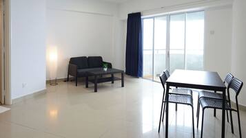 A modern living room with a sofa, a coffee table, and a dining table with chairs.