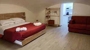 A bedroom with a wooden bed, a red sofa, and a walk-in closet. - Naples historic center cozy little house centrally located equipped with every comfort (Napoli)