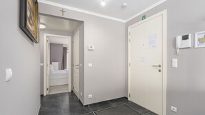 A hallway with a bed, a door with a cross, and a thermostat on the wall. - Pleasant apartment on the 2nd floor (Blankenberge)