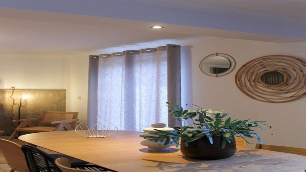 A dining area with a wooden table, chairs, a potted plant, and decorative wall art.