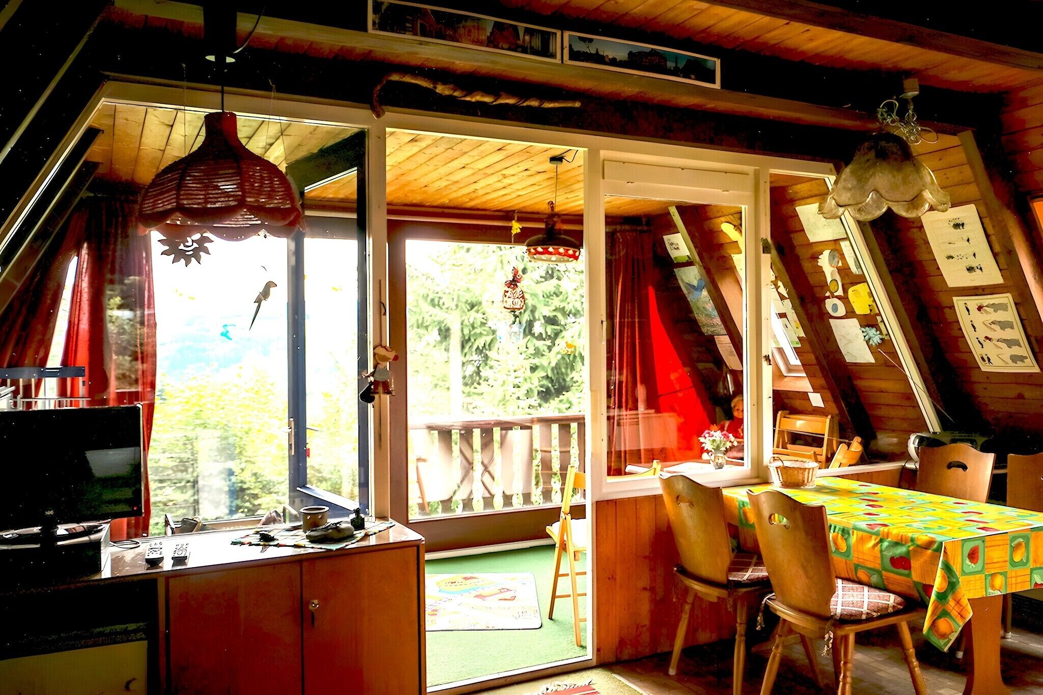 Ein gemütliches Zimmer mit Schreibtisch, Stuhl und Tisch, ein Balkon mit Aussicht und einer Hängelampe.