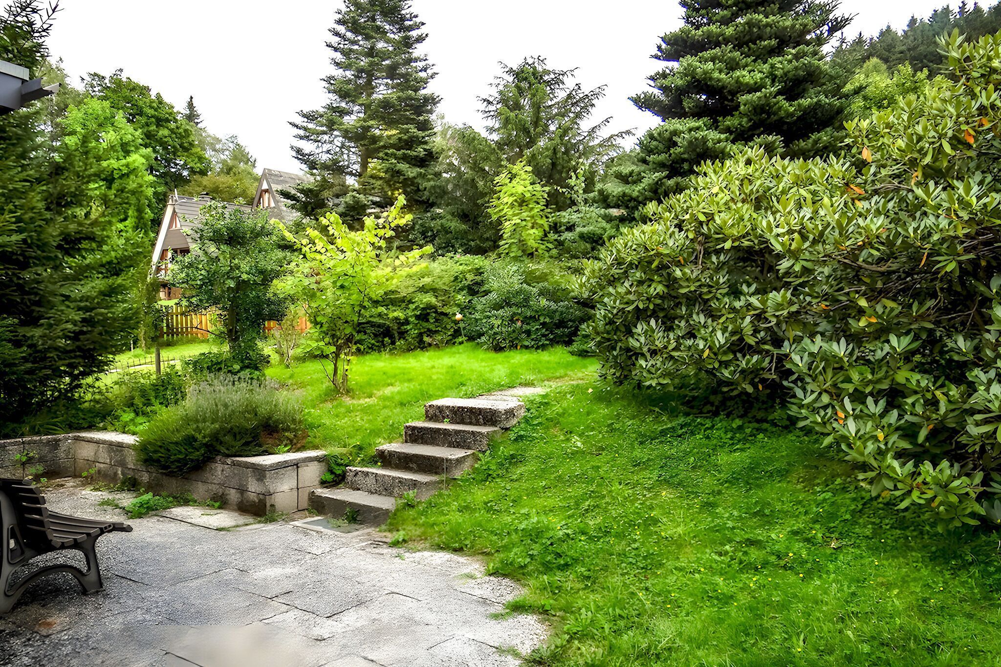 Eine steile Steintreppe führt über einen grasbewachsen Hang, umgeben von dichtem Grün und Bäumen.