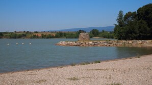Escena tranquila junto al lago, con una estructura de piedra y orilla pedregosa.