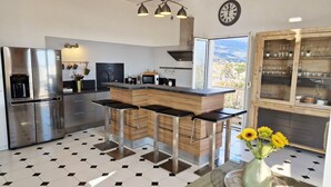 Een moderne keuken met een centraal eiland, roestvrijstalen apparatuur en een groot raam met uitzicht.