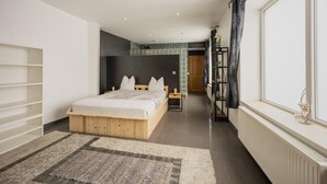 A modern bedroom with a wooden bed, a built-in wardrobe, a radiator, and a view through a window. - Holiday Home in Verviers with Sauna (Verviers)