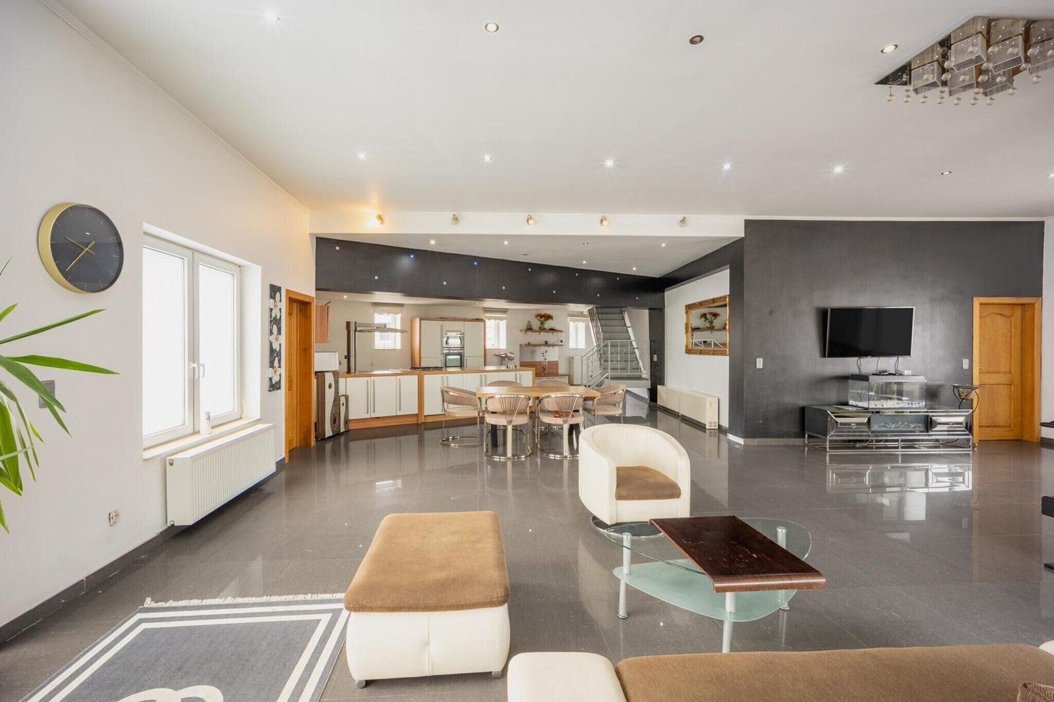 Un salón amplio con una mesa de comedor, sofás, un televisor y una escalera que sube a otro nivel.