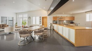 A modern kitchen with a central island, dining area with chairs, and a living space with a sofa and plants. - Holiday Home in Verviers with Sauna (Verviers)
