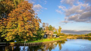 A riverside property with a house, a grassy area, and a dock. - Canal-Side Stay, Giethoorn (Giethoorn)