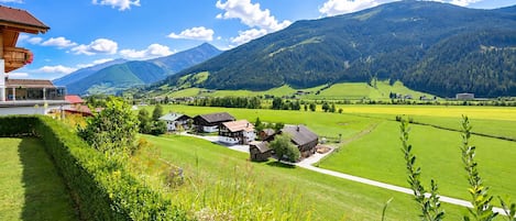 A rural landscape with houses, a clear sky, and mountains in the background.