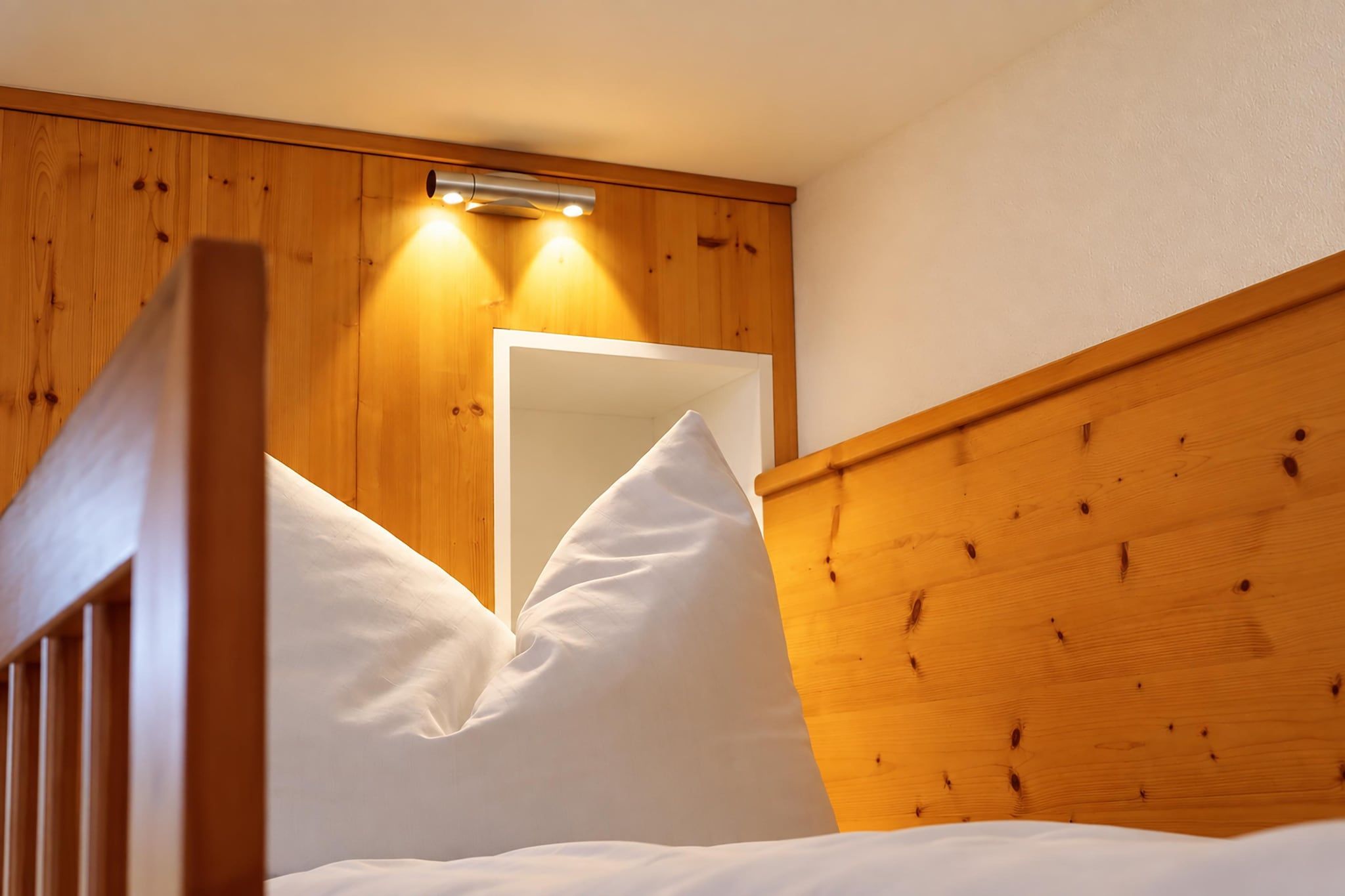 A wooden bunk bed with a headboard and a mirror.