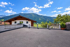 A chalet with a sloped roof, a balcony, and a view of a mountain range.