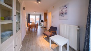 A modern living room with a dining area, a white table, and a chair. - Duplex apartment near the sea (Middelkerke)