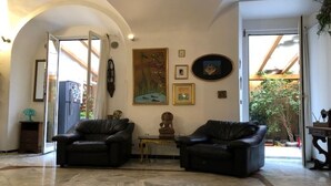 Uma sala de estar ampla com dois sofás de couro, piso de mármore e um quadro na parede.