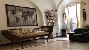 Uma sala de estar com sofá, estante de livros, mapa-múndi e área de jantar.