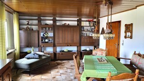 Un rincón comedor acogedor con una mesa y sillas de madera, un banco y una estantería llena de objetos decorativos.