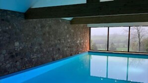 Une piscine aux murs en pierre, offrant une vue sur la campagne environnante.