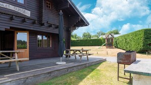 A wooden building with a sign reading "HALET SUISSE". There are picnic tables and a barbecue grill outside.