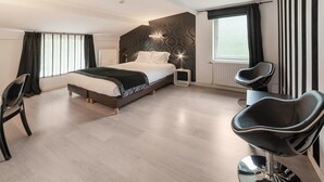 A modern bedroom with a large bed, a chair, and a desk.