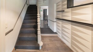 A staircase with a handrail, carpeted steps, and a wooden floor.