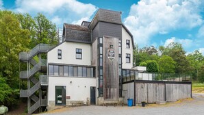 A building with a modern design, featuring a prominent wooden facade, a metal staircase, and a sign that reads "Adventure Valley." - Holiday Home in Durbuy near Adventure Valley (Durby)