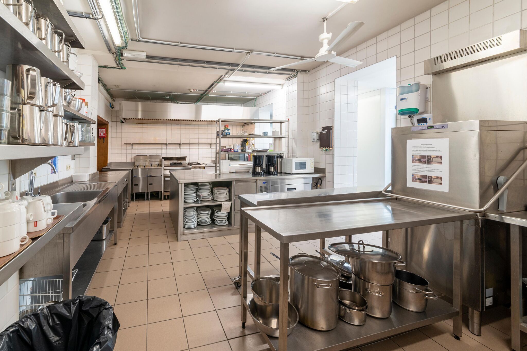 A modern kitchen with stainless steel appliances, a large island, and a variety of cookware.