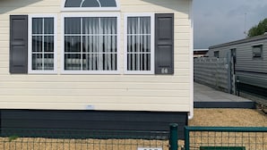 Une maison de plain-pied avec un toit à pignon, une fenêtre centrale dotée de volets et un petit porche.