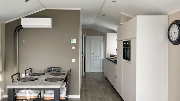 Une cuisine moderne avec des armoires blanches, un four encastré et une horloge au mur.