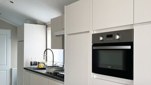Une cuisine moderne avec des meubles blancs, un four noir et un robinet en acier inoxydable.