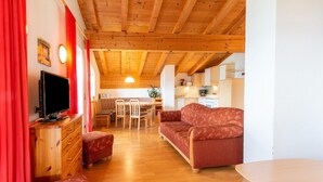 A cozy living room with a wooden ceiling, a sofa, a TV, and a dining area with chairs and a table. - Chalet in Gattererberg near Ski Slopes (Stummerberg)