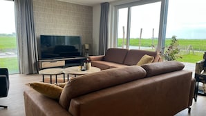 A modern living room with a leather sofa, a flat-screen TV, and a small round table. - Villa in Leons with Sloop Rental (Leons)