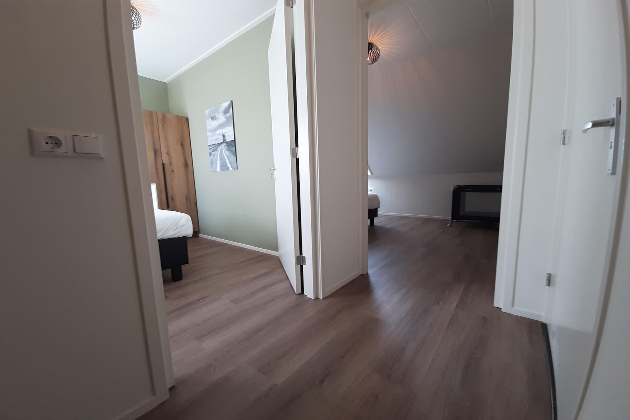 Ein Flur mit Holzboden, der zu einem Schlafzimmer mit Bett und Kleiderschrank führt.