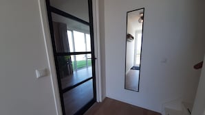 A hallway with a sliding glass door leading to a balcony, a large mirror on the wall, and a light switch. - Villa in Leons with Sloop Rental (Leons)