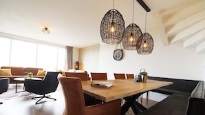 A modern dining area with a wooden table, leather chairs, and pendant lights. - Villa in Leons with Sloop Rental (Leons)