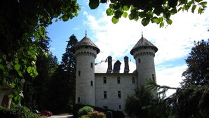 Un castillo con dos torres, rodeado de vegetación y un cielo despejado.