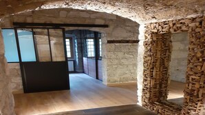 Una habitación con un arco de piedra, pared de madera y piso de baldosas.