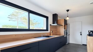 Une cuisine moderne dotée d’une grande fenêtre, de meubles de rangement aux couleurs sombres et d’un four encastré.