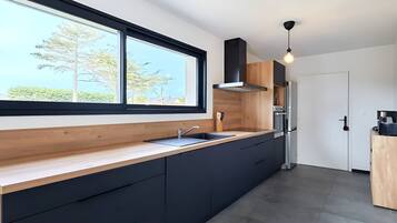 A modern kitchen with a large window, dark cabinetry, and a built-in oven.