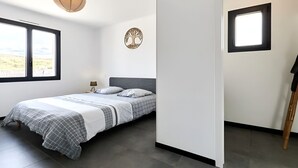 Une chambre à coucher avec un lit, une fenêtre, une lampe fixée au mur et une petite fenêtre.
