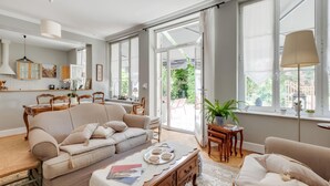 En rummelig stue med en stor sofa, et sofabord og et spiseområde med bord og stole.