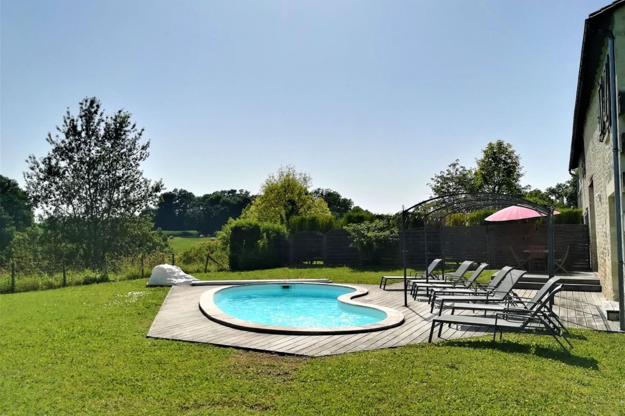 Un patio trasero con piscina, sillas de descanso y una zona de estar.
