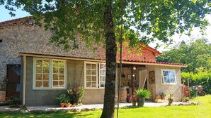 Une maison en pierre avec un toit en tuiles, de grandes fenêtres et un petit porche.