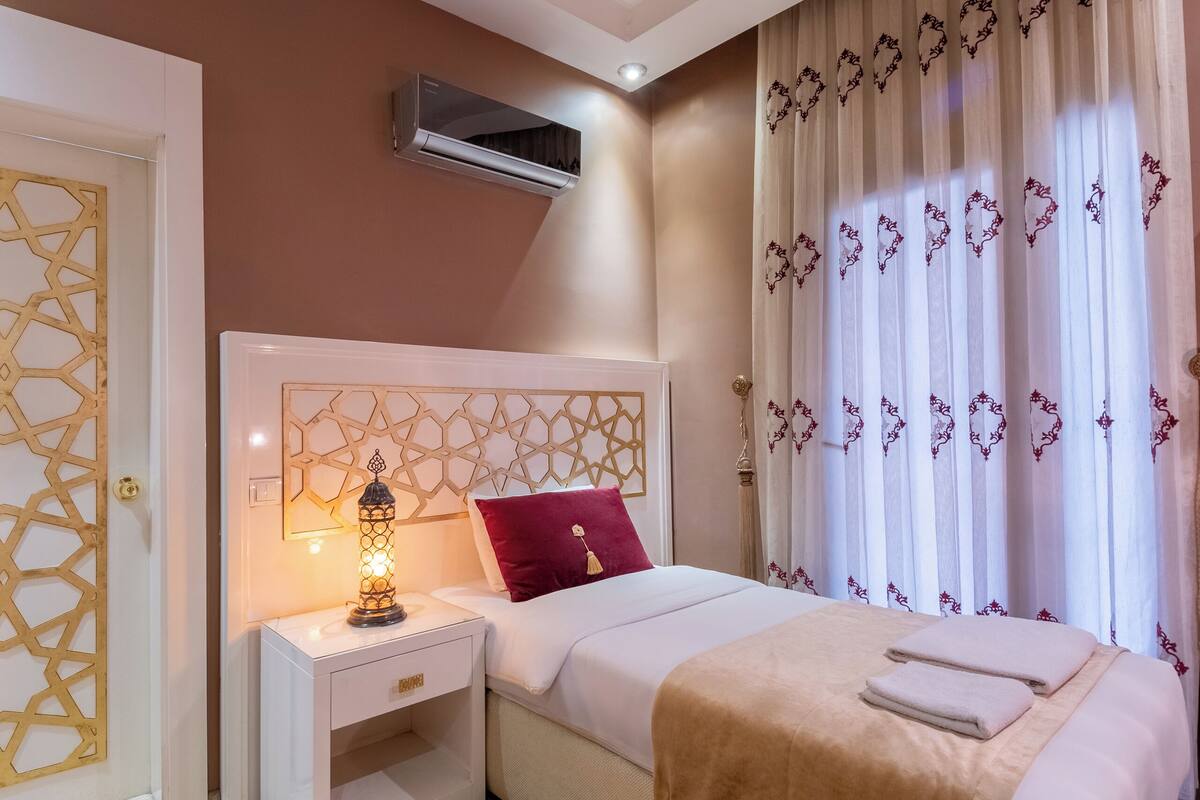 A bedroom with a bed, nightstand, lamp, and curtains.