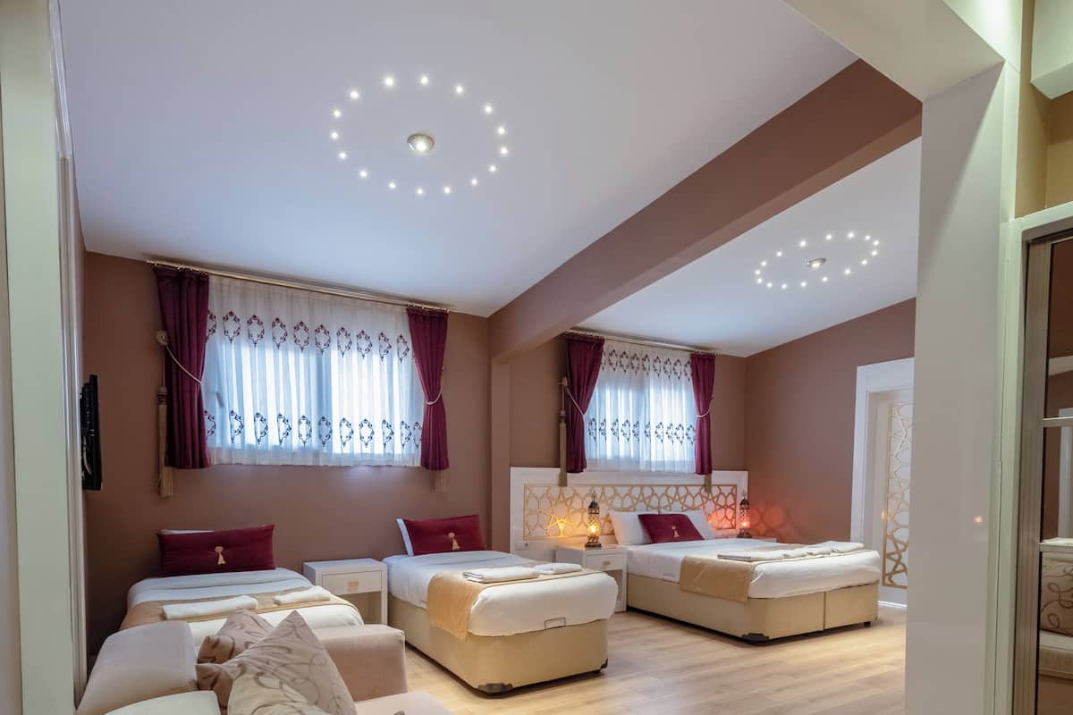 A spacious living area with a high ceiling, multiple seating options, and a large window with curtains.