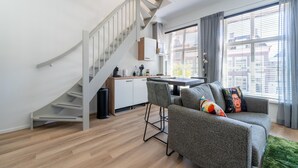 Una sala de estar moderna con una escalera, un comedor y vistas de la ciudad a través de amplios ventanales.