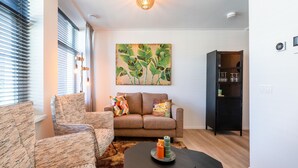 A modern living room with a sofa, armchairs, a coffee table, and a painting of leaves on the wall. - Modern renovated apartment in the heart of Sneek (Sneek)