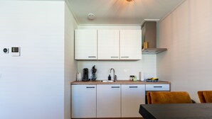 A compact kitchen with white cabinets, a wooden countertop, and a dining area with a table and chairs. - Modern renovated apartment in the heart of Sneek (Sneek)
