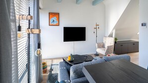 A modern living room with a flat-screen TV, a sofa, a coffee table, and a staircase leading to an upper level. - 2 modern apartments in the heart of Sneek (Sneek)