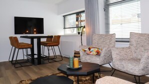 A modern living room with a black dining table, two brown chairs, a patterned sofa, and a black coffee table with candles. - 2 modern apartments in the heart of Sneek (Sneek)