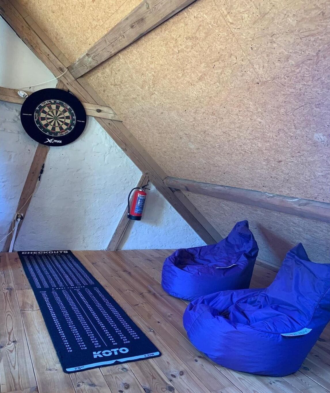 A loft room with a dartboard, a fire extinguisher, a KOTO mat, and two blue bean bags.