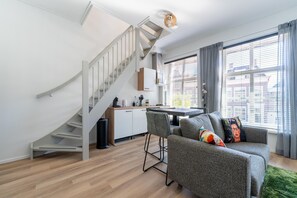Ein modernes Wohnzimmer mit Treppe, Essbereich und großem Fenster mit Vorhängen.